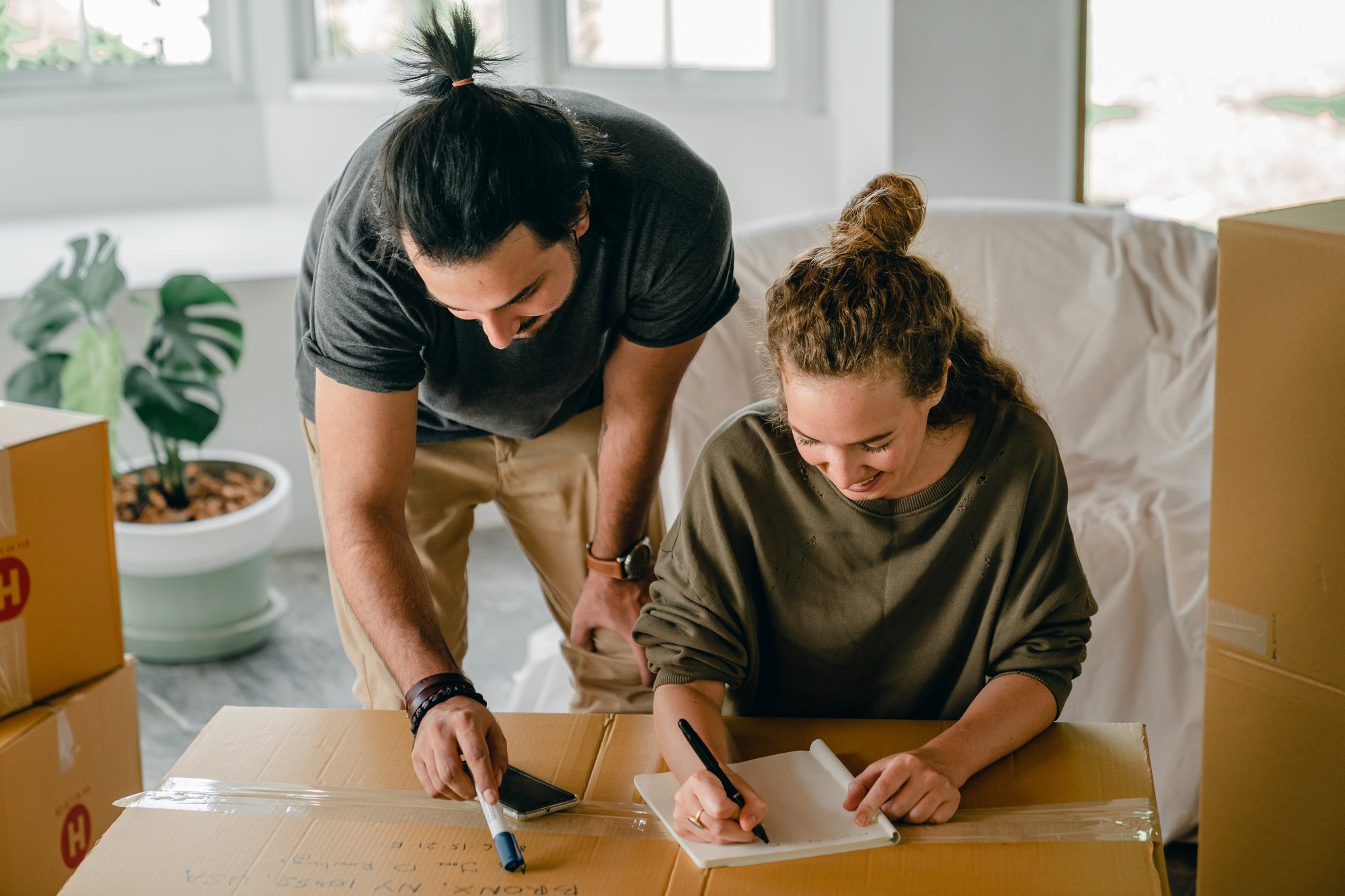 couple packing boxes while looking at a checklist