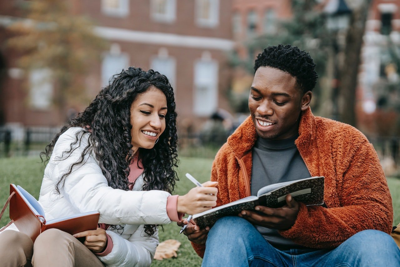 two students writing on a notebook
